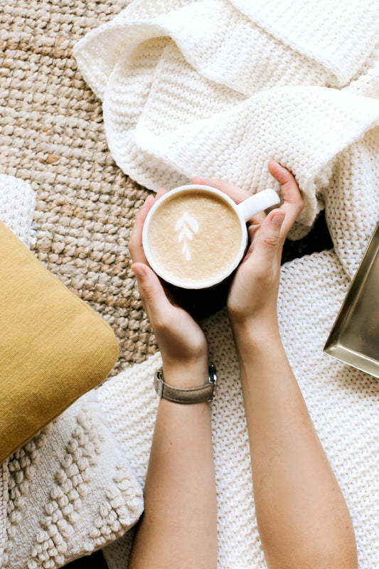 Mujer con taza de cafe en las manos y taza caliente entre las manos