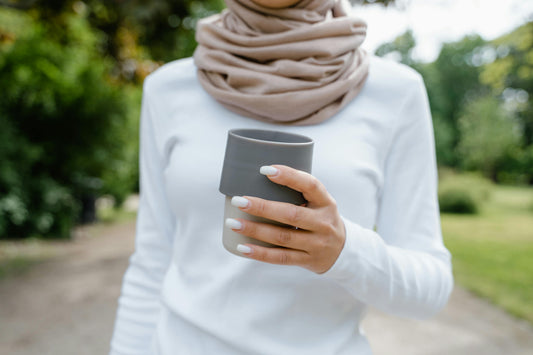 Mujer con taza de te en las manos caminando.