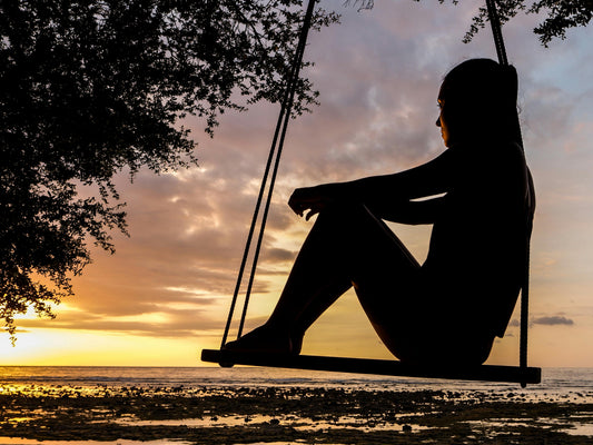 Mujer en su rincón favorito al atardecer, sosteniendo una taza humeante en un entorno íntimo y sereno.
